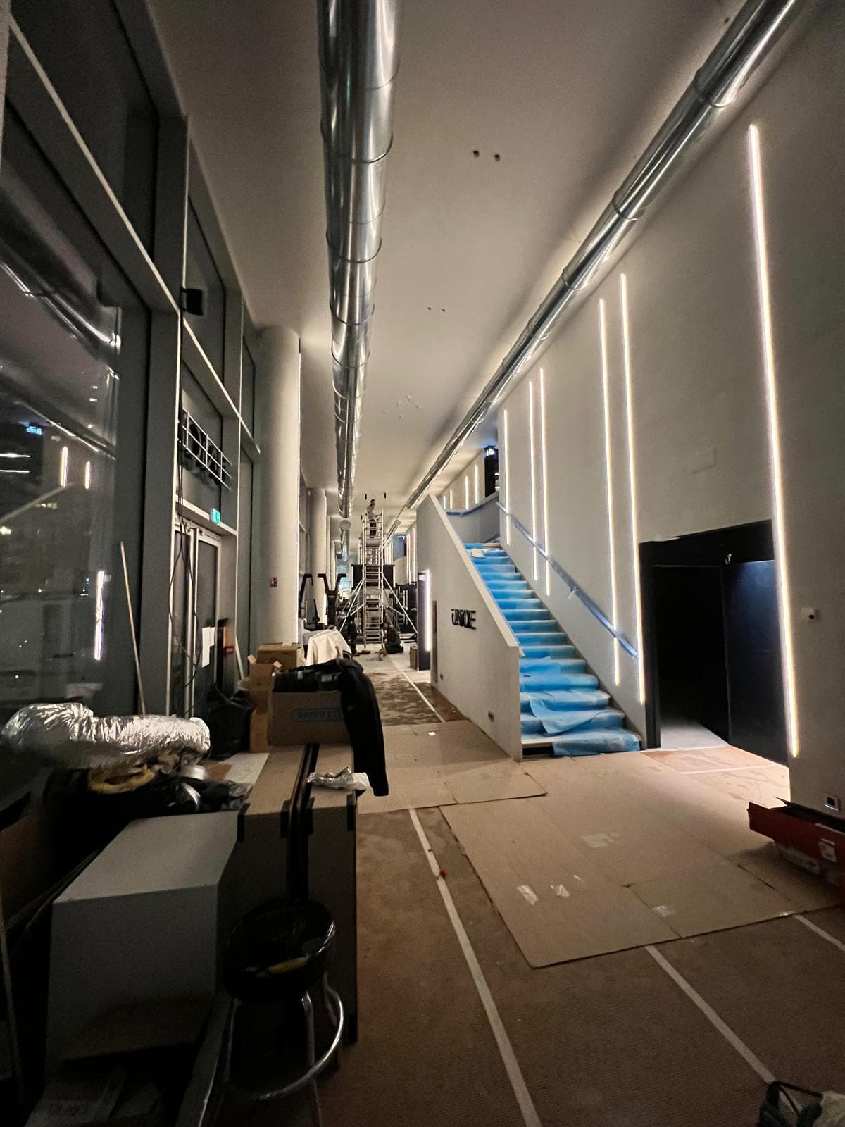 Couloir en cours de travaux : profilés LED posés et escalier éclairé